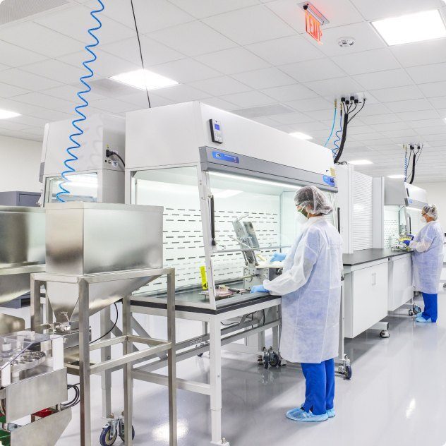Pharmacy staff in protective gowns working in a compounding cleanroom